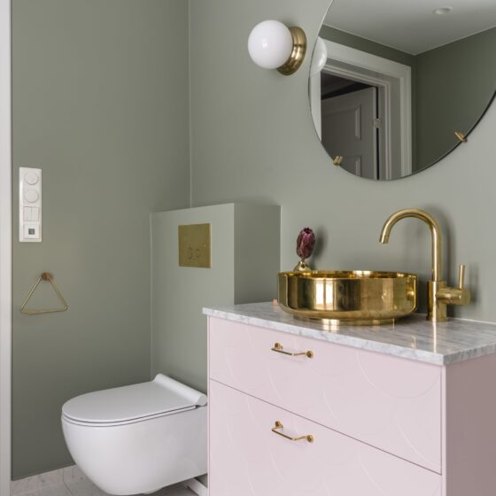Bad med grønne vegger og detaljer i rosa og messing, utført av Lomundal.