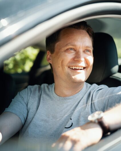 Johan er selger hos Lomundal, her sitter han i bilen sin og ser ut av vinduet i førersetet.