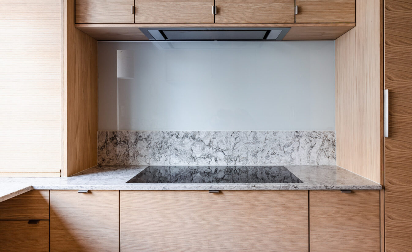 Detaljbilde fra kjøkken i eik fra Drømmekjøkkenet med grå og hvit benkeplate i stein. Utført av Lomundal.