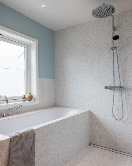 Moderne bad med dusj og badekar. Terrazzoflis på gulv og vegg sammen med Jotun Sjøgløtt. Utført av Lomundal.