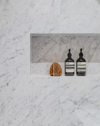 Detaljbilde av hyllenisje i dusjrom med hvit marmorfliser. Utført av Lomundal.