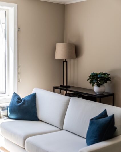 Nyoppusset stue med beige malte vegger, lys sofa og med blå dekorative puter. Utført av Lomundal.