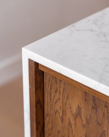 Detaljbilde av moderne mørkt kjøkken med lys benkeplate i kompositt.