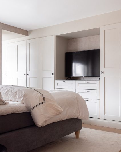 Lyst og moderne soverom med innebygd garderobeløsning og tapetserte vegger.