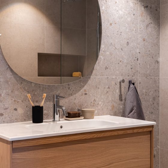 Minimalistisk bad med en kombinasjon av flekkede og nøytrale fliser.