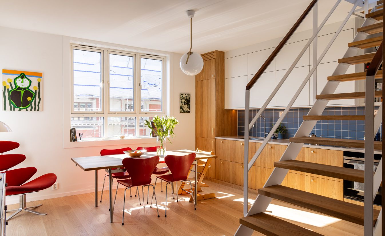 Moderne leilighet totalrenovert av Lomundal. Kjøkkenet er bygget av møbelsnekker med laminat og eikefinér med blå kvadratiske fliser som backsplash.