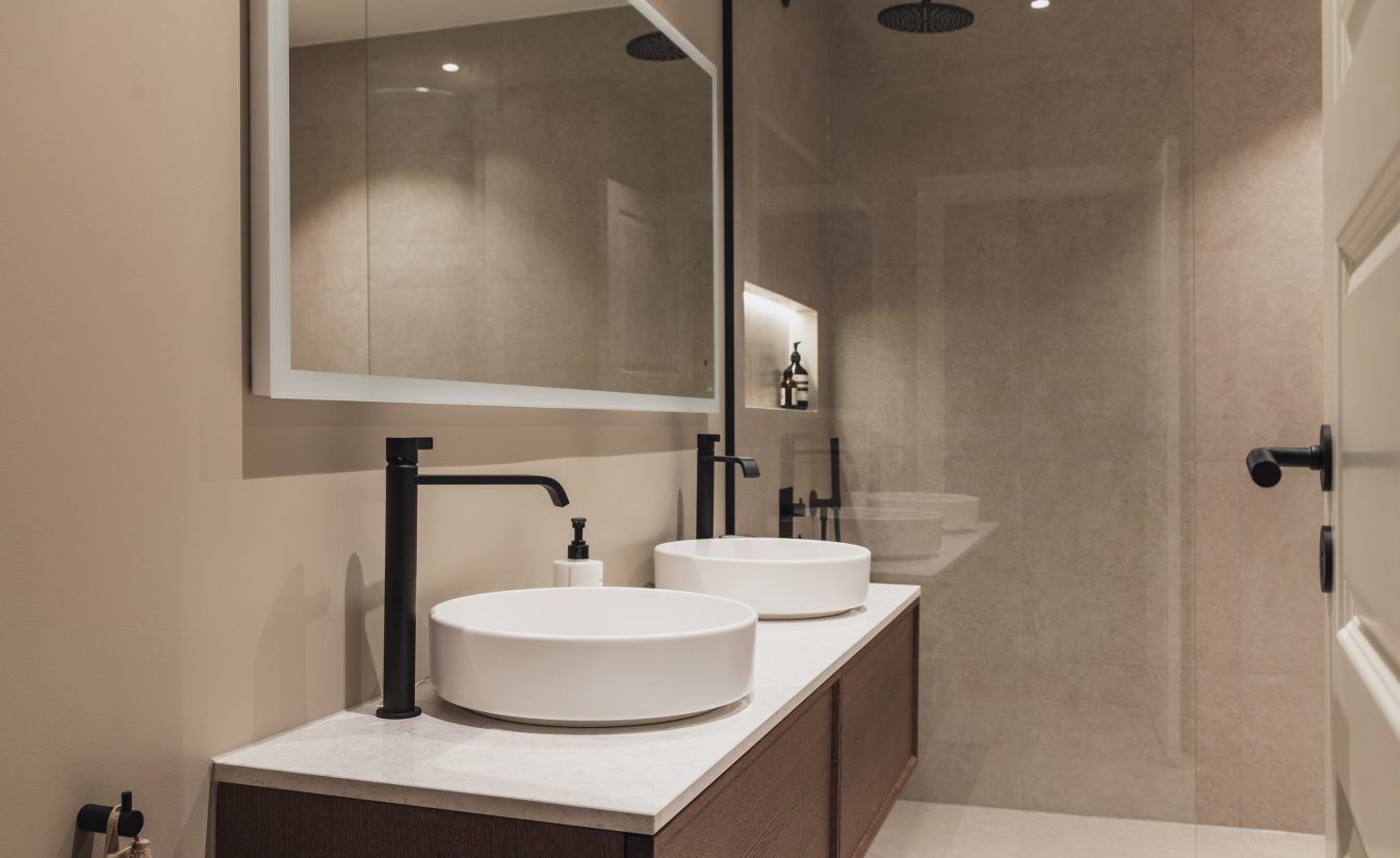 Bad i moderne stil med lyse store fliser på vegg og gulv og sorte detaljer. Utført av Lomundal.