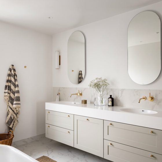 Lyst og klassisk baderom med spesialbygd baderomsinnredning i en lys grønn tone. Marmorfliser og detaljer i messing.