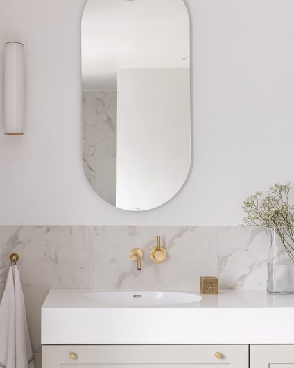 Lyst og klassisk baderom med spesialbygd baderomsinnredning i en lys grønn tone. Marmorfliser og detaljer i messing.