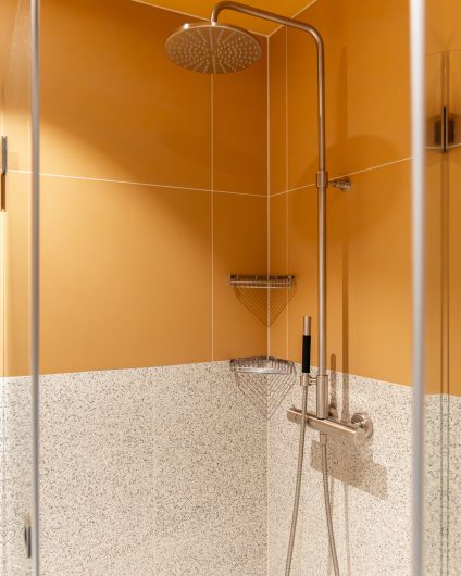 En moderne dusjsone med et retro og lekent uttrykk. Gulfargen og terrazzoflisene gir badet et unikt preg. Badet er totalrenovert av Lomundal.