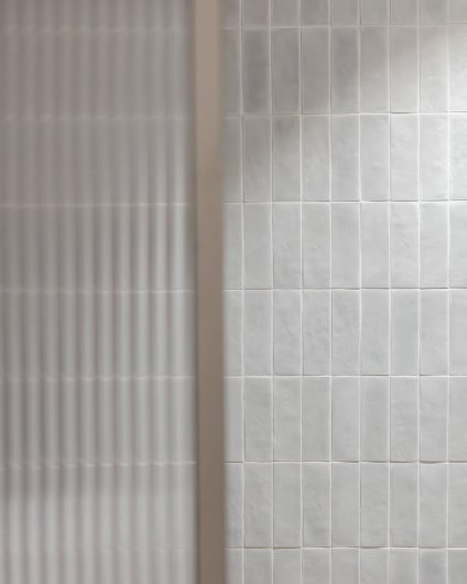 Et moderne bad med mosaikkfliser i en dus grønntone på vegg og dusjvegg i glass med rillet effekt. Utført av Lomundal.