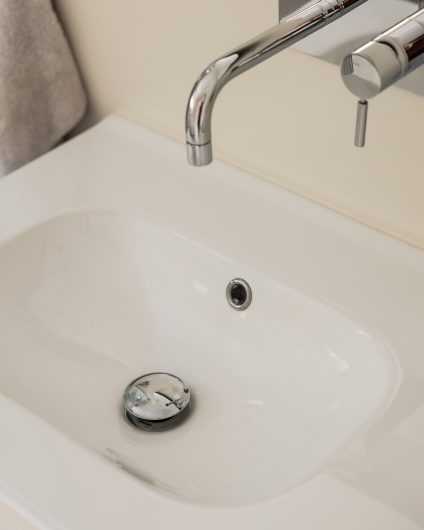 Detaljbilde av nyoppusset bad med tidløs armatur ved vask i krom. Utført av Lomundal.