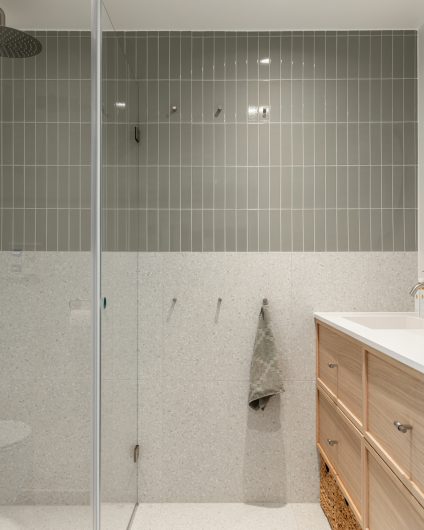 Totalrenovering av bad i skandinavisk stil med grønne, blanke fliser og terrazzofliser på vegg, samt gulv. Tidløs baderomsinnredning i lyst tre. Utført av Lomundal.