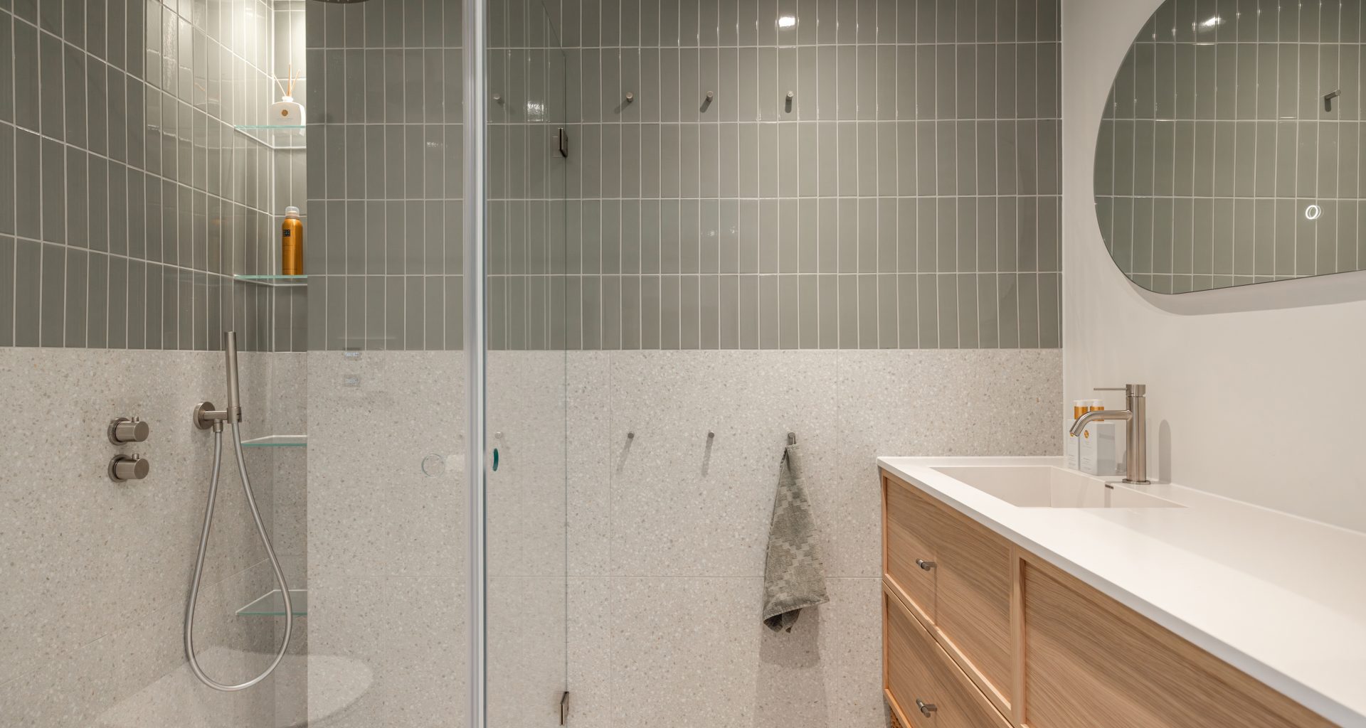 Totalrenovering av bad i skandinavisk stil med grønne, blanke fliser og terrazzofliser på vegg, samt gulv. Tidløs baderomsinnredning i lyst tre. Utført av Lomundal.