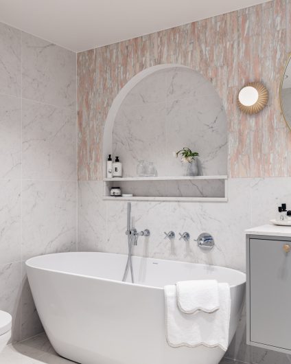 Eksklusivt, klassisk bad i lyse, delikate fargetoner. Badet er flislagt med norsk, rosa Fauske marmor og Carrara marmor. Badet har et frittstående badekar og en buet dusjnisje på vegg. Utført av Lomundal.