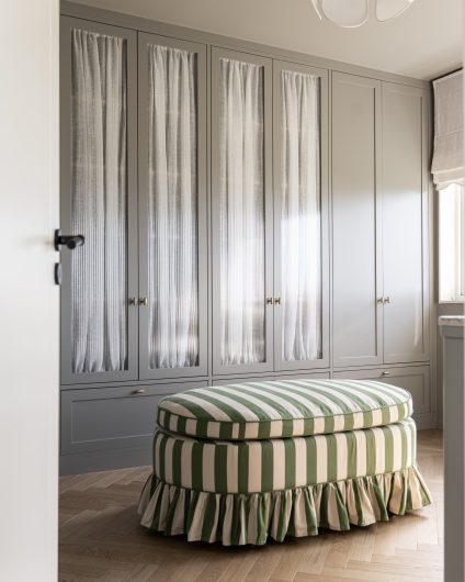 Walk-in garderobe med skap i gråtoner, med rillet glass og fiskebensparkett i lys eik. Utført av Lomundal.
