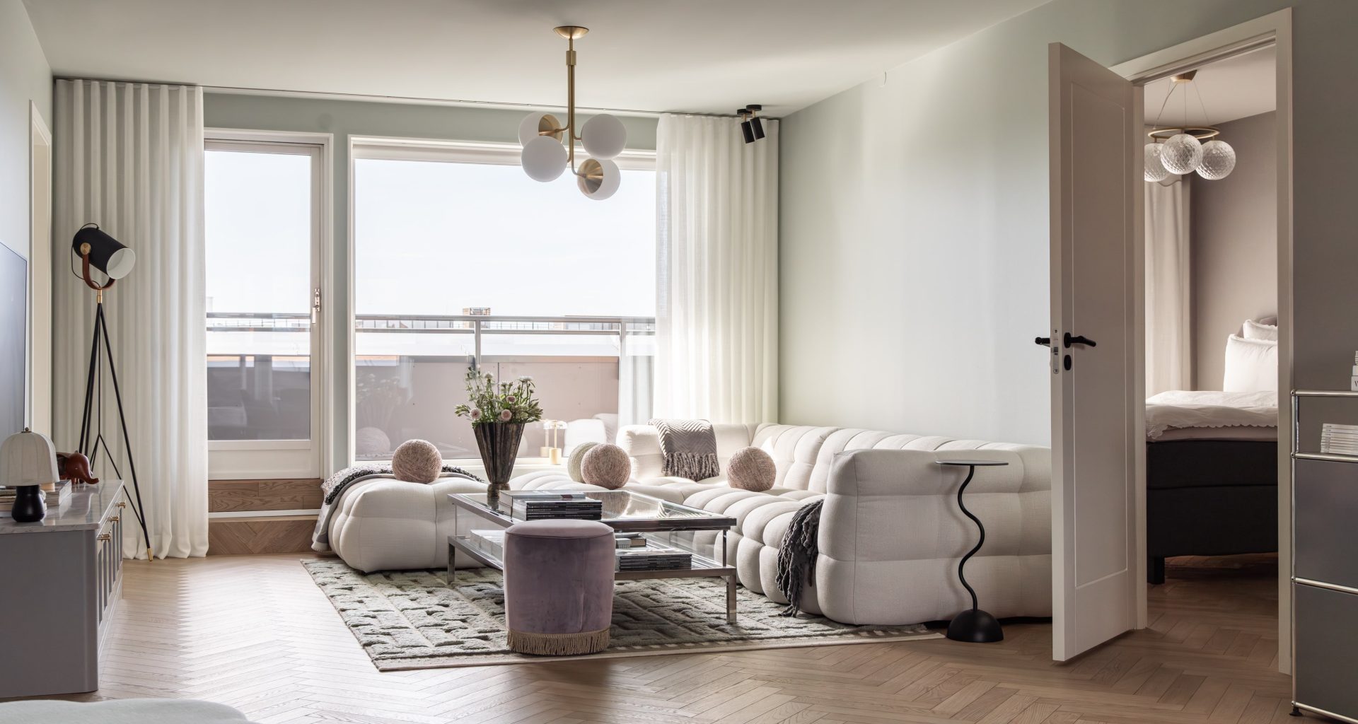 Moderne stue med innredning i lyse toner og en vegger i en dempet mintgrønn tone. Gulvet er en lys eikeparkett med fiskebensmønster. Utført av Lomundal.