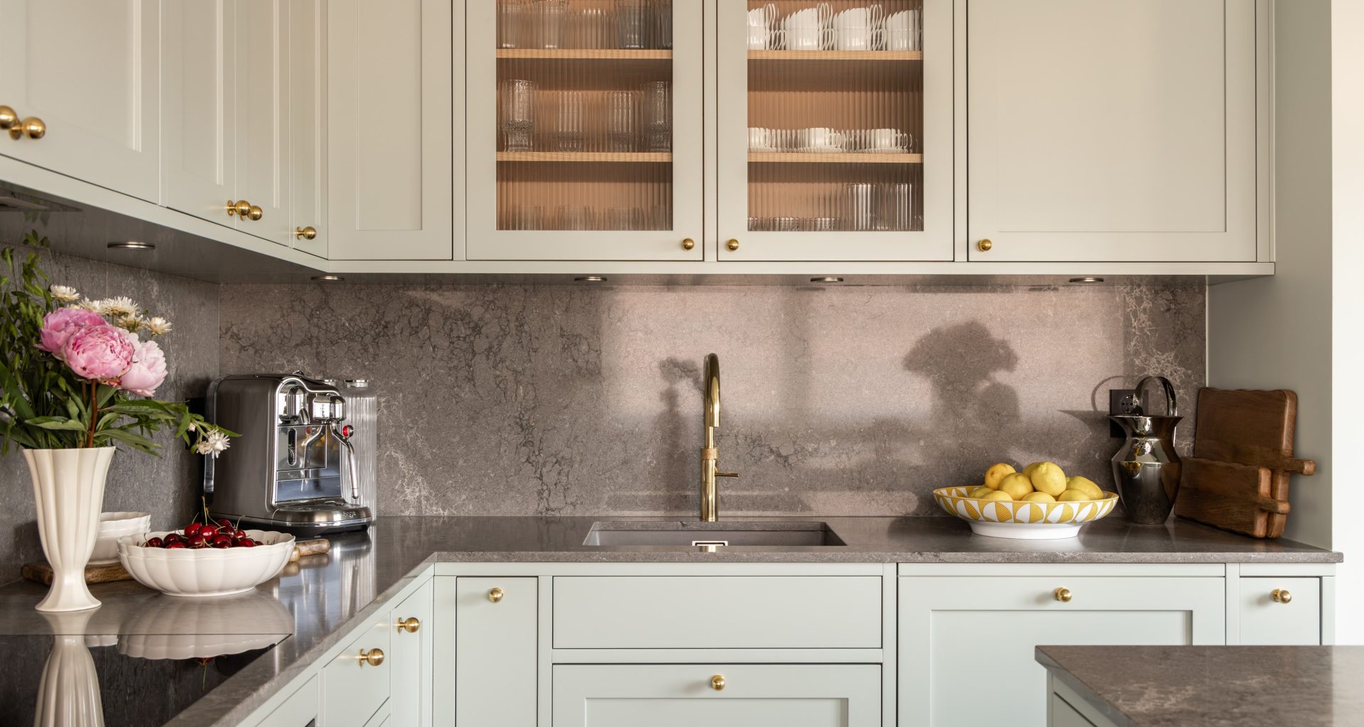 Klassisk kjøkken i en mintgrønn tone. Kjøkkenet har et klassisk uttrykk med profilerte kjøkkenfronter og rillet glass. Benkeplaten og backsplashet er i kvartskomposittstein som skaper en fin kontrast. Utført av Lomundal.