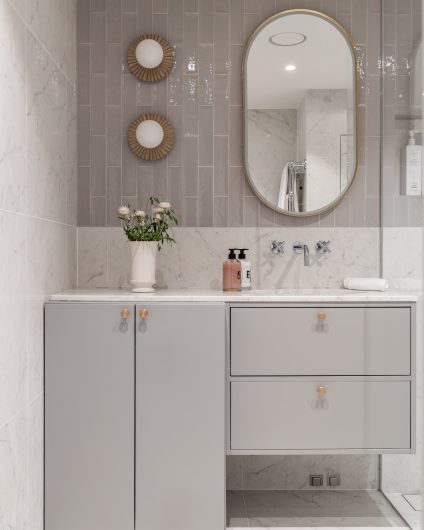 Moderne bad i gråtoner. Badet har et stilrent uttrykk med Carrara og blanke fliser på vegg. Badet har praktiske løsninger med innebygd vaskemaskin. Utført av Lomundal.