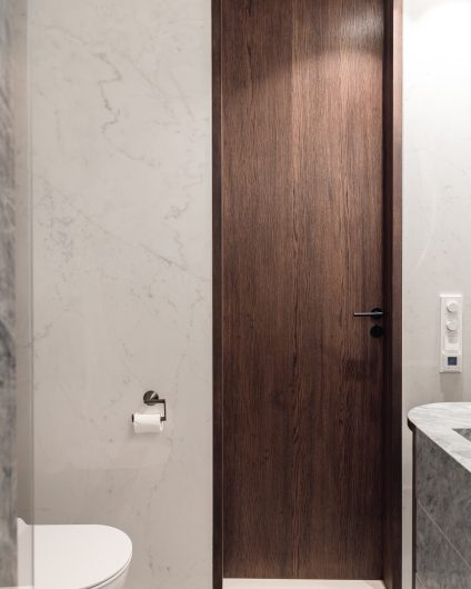 Moderne bad med marmorfliser og dør i mørkt treverk. Badet har en elegant og stilrent innredning. Utført av Lomundal.