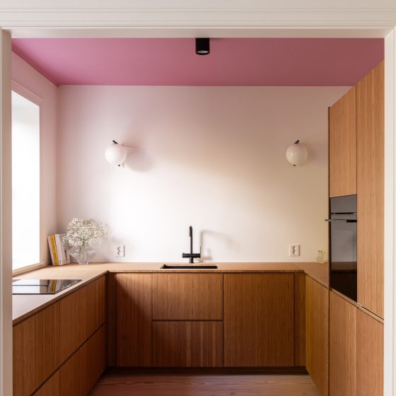 Lyst kjøkken med kjøkkeninnredning i bambus, vegger malt i klassisk hvit, og tak malt i en lekker rosafarge.