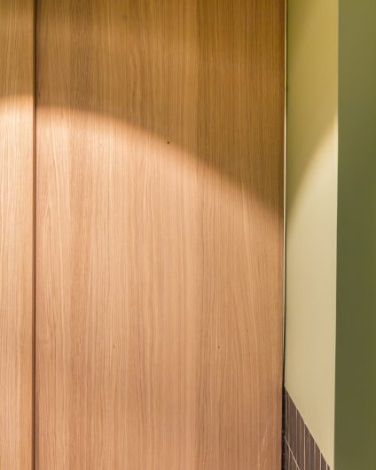 Moderne bad i grønntoner med plassbygd høyskap med skyvedør fra møbelsnekker.