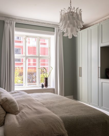 Klassisk soverom i en dus grønnfarge med hvite, elegante stukkaturlister og rosett. Rommet har en behagelig og lys atmosfære, og plassbygd skap. Utført av Lomundal.