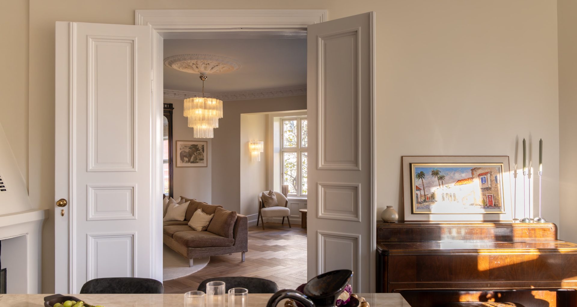 Klassisk bolig i lyse, nøytrale fargetoner og elegante fløydører med håndtak i messing som skiller kjøkken og stue. Utført av Lomundal.