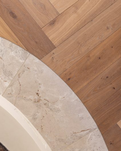 Detaljbilde av parkett i stue og gulvfliser rundt peis. Materialer av kvalitet med et tidløst uttrykk. Utført av Lomundal.