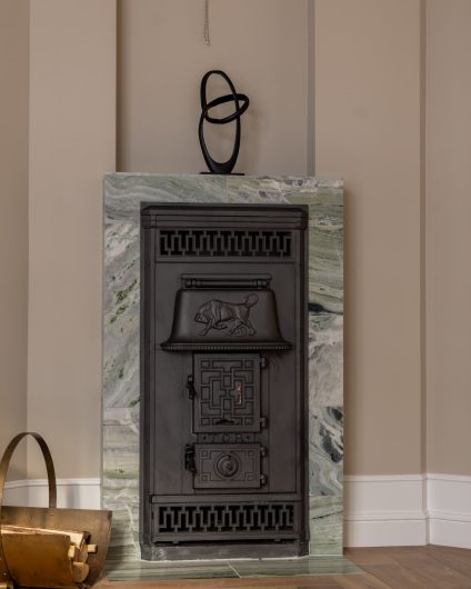 Elegant peis med et majestetisk uttrykk innrammet i blågrønn naturstein. Utført av Lomundal.