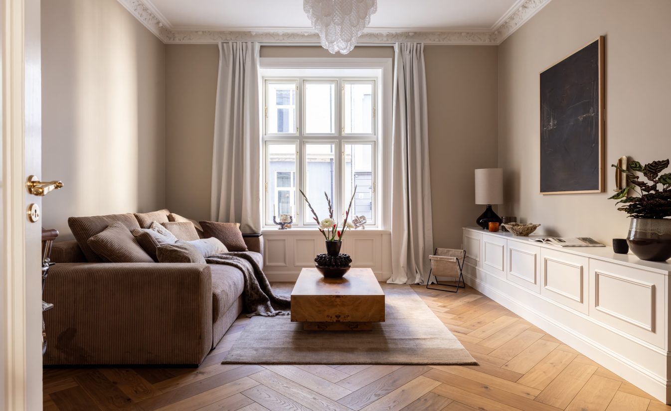 Klassisk stue i beigetoner med elegante stukkaturer og fiskebensparkett. Utført av Lomundal.