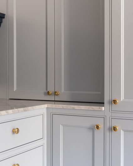 Kjøkkeninnredning i en lys blå farge med detaljer i messing, kombinert med en eksklusiv benkeplate i Carrara marmor. Utført av Lomundal.