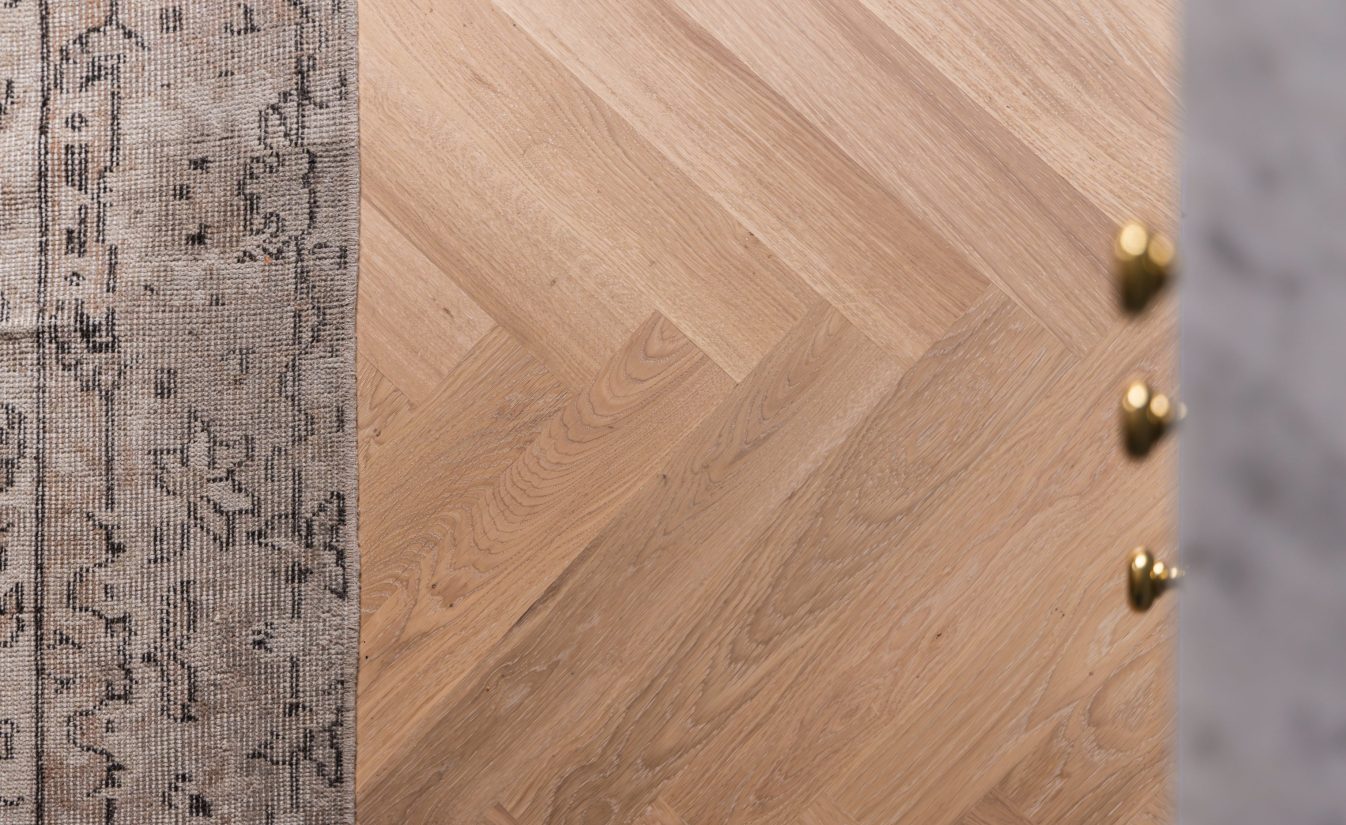 Detaljbilde av lys fiskebensparkett på kjøkken. Utført av Lomundal.