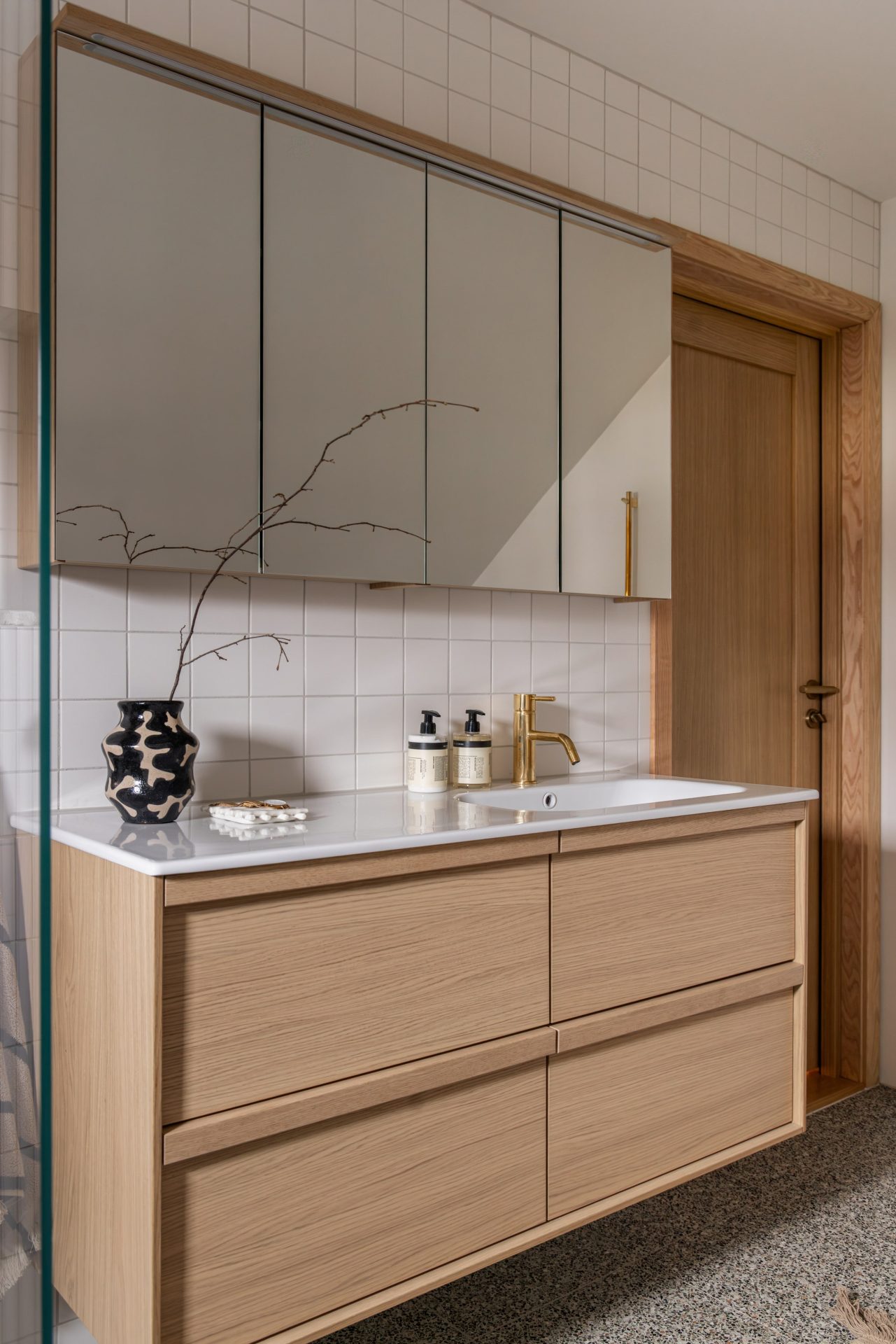 Bad i lyse toner med terrazzoflis og detaljer i messing - Bilde