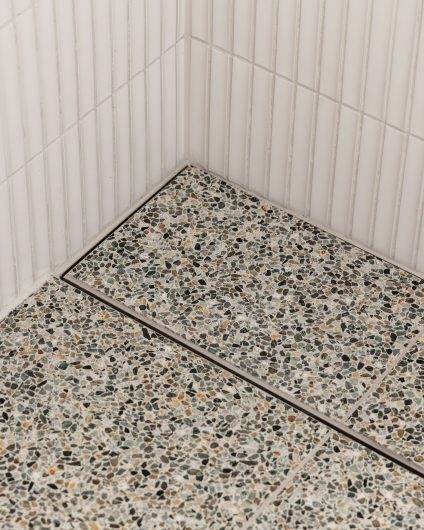 Dusjsone med innebygd sluk, terrazzofliser på gulv og kit-kat fliser på vegg. Utført av Lomundal.