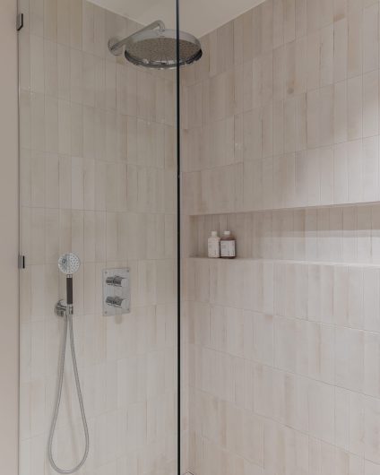 Klassisk dusjsone med en lang dusjnisje og blanke mosaikkfliser på vegg. Totalrenoveringen er utført av Lomundal.