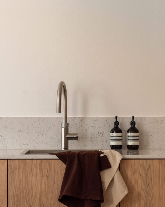 Kjøkken i skandinavisk stil med innredning i eik og kompositt benkeplate og backsplash. Totalrenoveringen er utført av Lomundal.