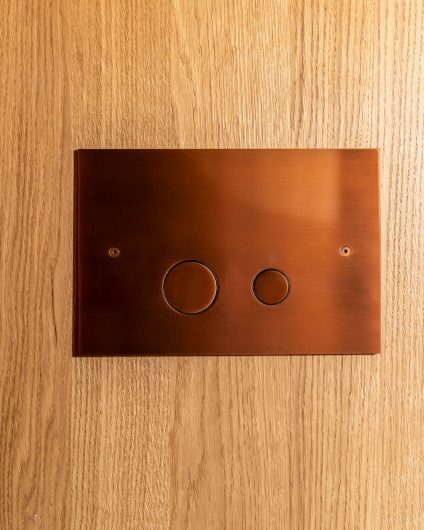 Baderomsvegg i lys eikefinér med bronsedetaljer. Utført av Lomundal.