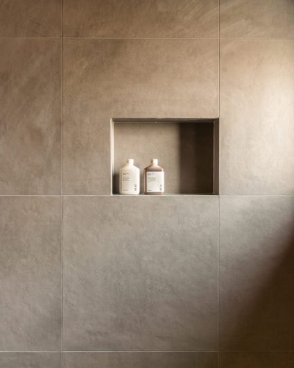 Moderne dusjsone med grå fliser og hyllenisje. Utført av Lomundal.