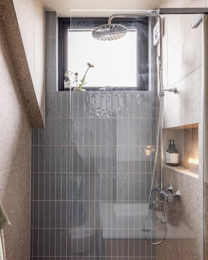 Gjestebad med en dusj og dusjnisje med et moderne og stilrent uttrykk. Badet er totalrenovert av Lomundal.