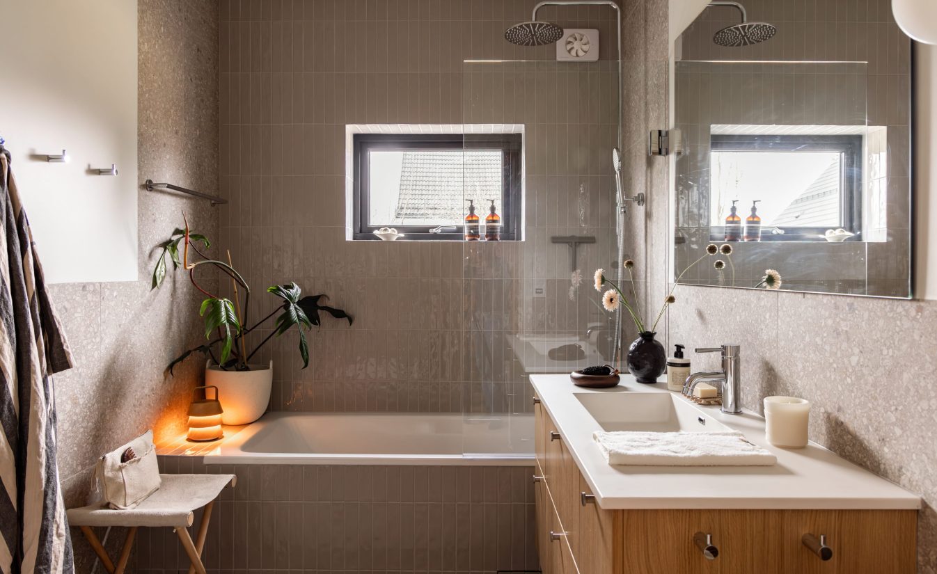 Master bad med blanke fliser i dusjsonen, terrazzofliser på vegg og baderomsinnredning i lyst treverk. Badet er totalrenovert av Lomundal.