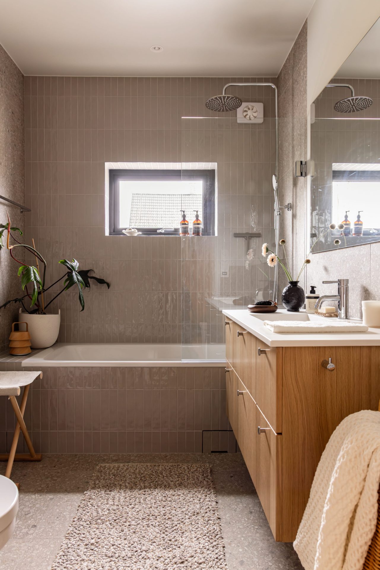 Skandinavisk bad med blå, blanke fliser i dusjsonen, terrazzoflis på gulv og vegger og baderomsinnredning i lyst treverk med armaturer i krom. Badet er totalrenovert av Lomundal. - Bilde