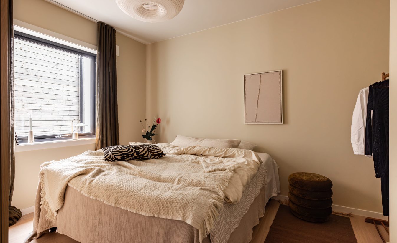 Et behagelig soverom med dagslys, med vegger malt i en lys beigefarge og med en lys parkett på gulv. Soverommet er totalrenovert av Lomundal.