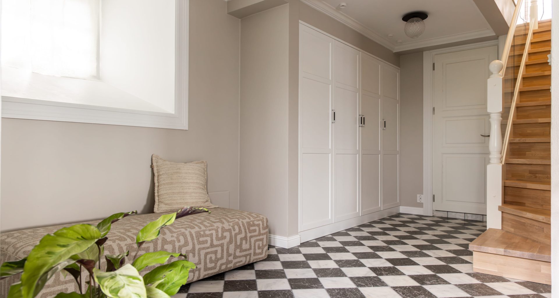 Entré i klassisk stil med gulvfliser i sjakkmønster, beige vegger og innebygd garderobe med elegant uttrykk. Utført av Lomundal.