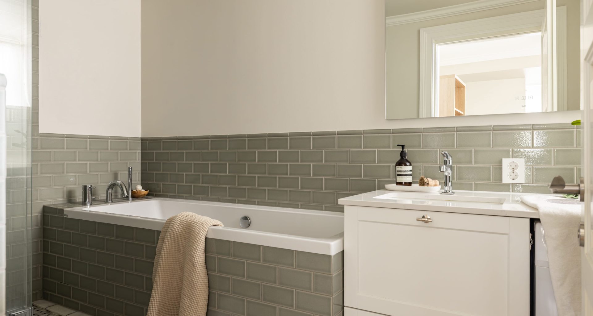 Klassisk bad med veggfliser i en dus grønntone. Badet har et tidløst uttrykk med en elegant kombinasjon av materialer og mønstre. Utført av Lomundal.