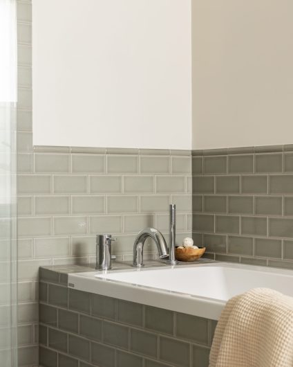Baderom i klassisk stil med et elegant badekar og fliser i duse grønntoner med en blank finish. Utført av Lomundal.
