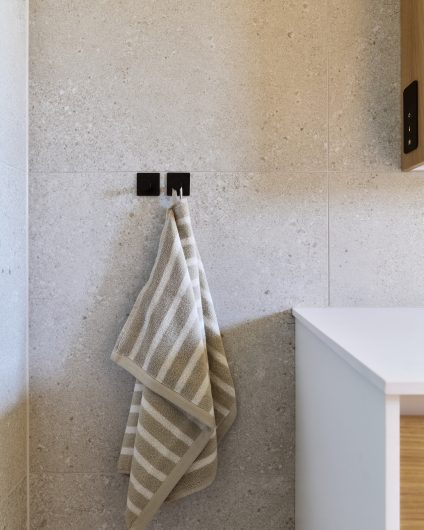 Beige fliser med naturlig spill på baderomsvegg. Utført av Lomundal.