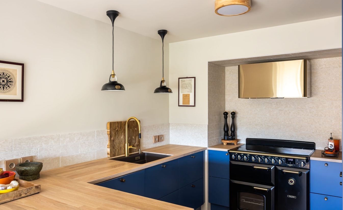 Moderne kjøkken med fronter i blåtoner, svart ovn, benkeplate i eik og detaljer i messing. Totalrenoveringen er utført av Lomundal.