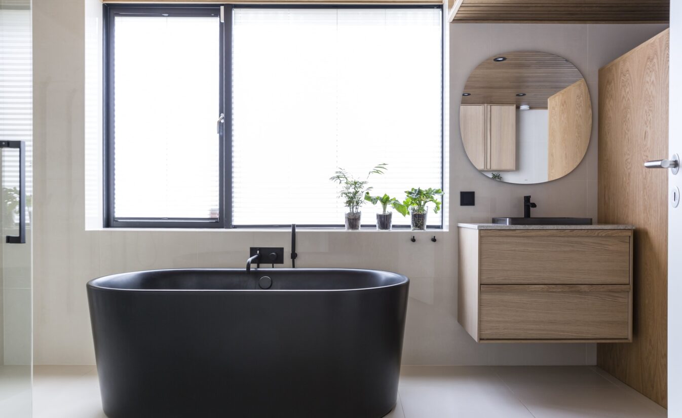 Bad med sort badekar og møblement i eik, utført av Lomundal.