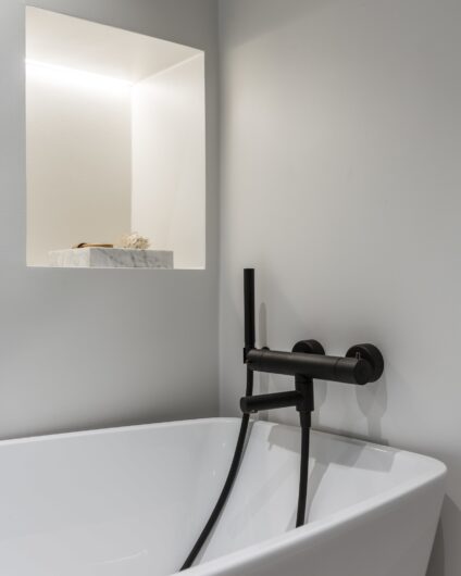 Detaljbilde fra bad med hvitt badekar og innbygd armatur i matt sort, utført av Lomundal.